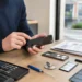 Persoon bekijkt een smartphone met gebarsten scherm op een reparatietafel met gereedschap.